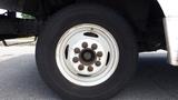 Close-up of a white wheel and tire belonging to a 2011 Ford Econoline showing visible rust and multiple lug nuts