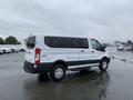 A 2017 Ford Transit van with a white exterior and black accents viewed from the side at an angle