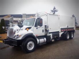 A white 2008 International 7400 truck with a large cargo box and several wheels parked on a wet surface