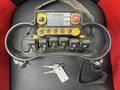 Control panel of a 2006 International 7500 featuring multiple switches buttons and a small display with a yellow border and keys attached to the side