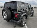 A black 2019 Jeep Wrangler parked with a spare tire mounted on the rear door and five-spoke alloy wheels