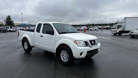 A white 2016 Nissan Frontier pickup truck parked with its driver's side facing forward