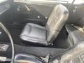 Interior view of a 1966 Ford Mustang featuring black leather seats and a classic dashboard design