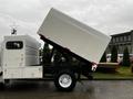 A 2007 Freightliner M2 106 truck with a raised dump box revealing the truck's bed and lifting mechanism