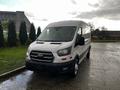 A white 2020 Ford Transit van with a sleek design and large front grille parked on a wet surface