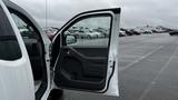 A 2016 Nissan Frontier with an open driver's side door showcasing the interior door panel and handle