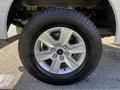 A silver alloy wheel with six spokes mounted on a tire showing a tread pattern designed for off-road performance