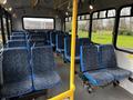 Interior of a 2015 Chevrolet Express with blue patterned seats arranged in rows along the sides and a central pole for support