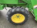 A close-up of a large black tire on a green tractor with a yellow rim and tread pattern designed for traction on various terrains