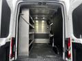 A 2021 Ford Transit van with a spacious, empty interior featuring metal shelving units along one side and gray flooring