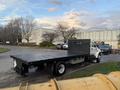 A white 2006 Ford F-650 flatbed truck is parked with a black flatbed in the foreground