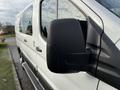 A 2023 Ford Transit van with a focus on the driver's side mirror and a sleek white exterior