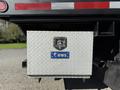 A metal tool storage box with a diamond plate finish and a lock labeled UWS mounted on the side of a truck