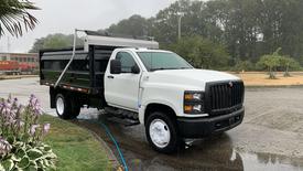 A white 2021 International CV515 dump truck with a black bed parked with water running off it