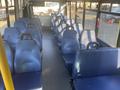 Interior view of a 2017 Chevrolet Express bus featuring rows of blue passenger seats with high backs and metal handrails