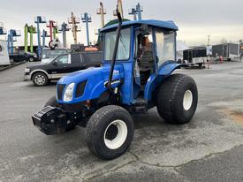 A blue 2007 New Holland TN70A tractor with large tires and a cab featuring a transparent cover and a front attachment visible