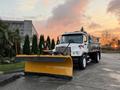 A white 2006 Freightliner M2 106 truck equipped with a large yellow snow plow mounted at the front