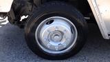 A close-up of a silver wheel with multiple lug nuts mounted on a black tire