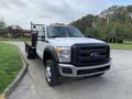 A 2012 Ford F-550 truck with a flatbed and a black grille displaying the Ford logo in the front