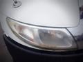 A close-up view of the front headlight and grille of a 2006 International 4300 with wet surfaces showing reflections and some dirt on the headlight