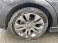 A close-up of a 2014 Subaru Impreza's alloy wheel showing a silver rim and a wet tire with visible tread patterns