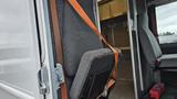 A 2006 Ford Econoline with a grey seat secured by an orange strap and an empty interior visible behind the front seats