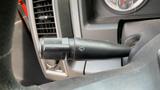 A black windshield wiper control stalk with a washer symbol attached to the steering column of a 2013 RAM 2500