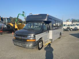 A 2017 Chevrolet Express bus with a predominantly black front and silver body features large windows and a step for entry