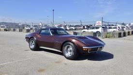 A 1971 Chevrolet Corvette Stingray in a deep brown color with a sleek design and chrome wheels positioned at an angle to showcase its iconic shape