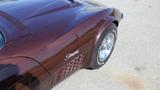 A 1971 Chevrolet Corvette Stingray in a deep burgundy color with chrome wheels and white-lettered tires showcasing its distinctive side vent and sleek design