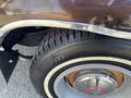 Close-up of a 1982 Mercury Grand Marquis tire and chrome wheel rim with visible tread patterns and a slightly damaged fender edge