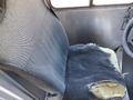 A worn driver seat of a 2008 Ford Econoline with frayed fabric and exposed foam on one side