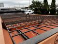 A close-up view of a metal grid structure on top of an orange vehicle bed with a metal hook in the center