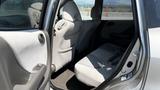 Interior view of a 2006 Honda Fit showcasing the rear seating area with light gray fabric seats and a foldable rear seatback