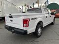 A white 2017 Ford F-150 with a crew cab and 4x4 insignia parked in a lot showcasing its rear and side profile