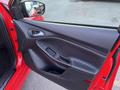 The image shows the interior door panel of a 2018 Ford Focus featuring a black armrest and window controls in a red car