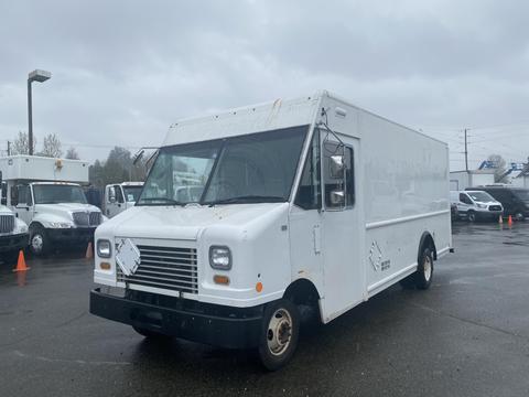 A white 2012 Ford Econoline delivery truck with a boxy shape and large front windows parked in a lot