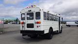 A 2015 International PC105 white school bus with multiple lights on top and a rear loading door