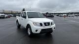 A white 2016 Nissan Frontier pickup truck is facing forward with a visible front grille and headlights