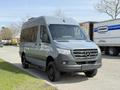 A 2019 Mercedes-Benz Sprinter van in gray parked with a front view showcasing its distinctive grille and streamlined design