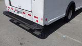 A 2011 Ford Econoline van with a white body and black rear bumper standing on a paved surface