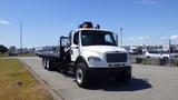 A white 2017 Freightliner M2 106 flatbed truck with a black flatbed and a crane mounted on the cab