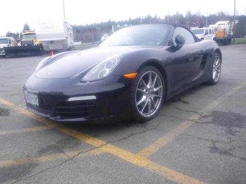 A black 2016 Porsche Boxster with a convertible top and silver sports wheels parked at an angle with its front facing towards the viewer