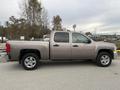 2013 Chevrolet Silverado Hybrid in silver with a crew cab and four doors parked on a graveled area