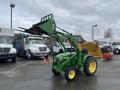 A 2003 John Deere 790 tractor with a front loader and bucket raised, featuring a green body and yellow wheels, positioned on a pavement surface