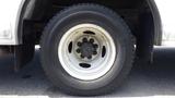 A close-up of a white wheel with a black tire mounted on a 2011 Ford Econoline