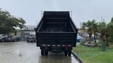 A 2021 International CV515 dump truck parked with its bed raised in a rainstorm