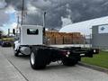 A white 2014 Kenworth T370 truck chassis facing right with a single exhaust pipe and a flatbed ready for cargo