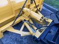 A yellow snow plow attachment with hydraulic arms and hoses connected to the frame of a truck