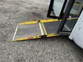 A yellow wheelchair ramp extended from a 2017 Chevrolet Express van with a black surface for traction